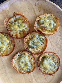 four small muffins on a wooden plate with cheese and sauce in the middle