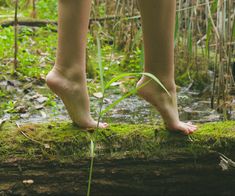 a person standing on a log with their feet in the air and one foot above the ground