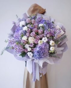 a woman holding a purple and white bouquet