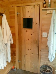 there are many towels hanging on the wall in this bathroom with wooden walls and flooring