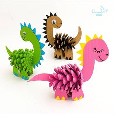 three paper dinosaurs with pine cones on their heads and one dinosaur holding a pine cone