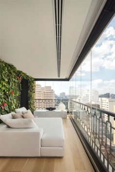 a white couch sitting on top of a hard wood floor next to a tall window