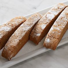 four pieces of bread sitting on top of a white plate next to some powdered sugar