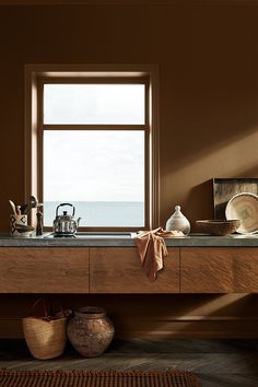 a kitchen counter with pots and pans on it next to a window overlooking the ocean