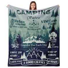 a woman is holding up a towel with the words camping on it and trees in the background