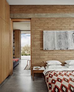 a bedroom with brick walls and a large painting hanging on the wall above the bed