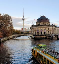 a yellow boat traveling down a river next to a tall building with a dome on top