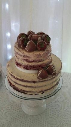 a three layer cake with chocolate covered strawberries on top and white lace tablecloth