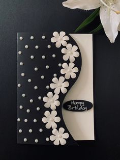 a black and white birthday card with flowers on the front, next to a flower bouquet