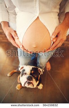 a woman holding her belly while standing next to a dog