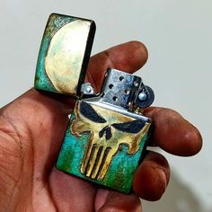 a hand holding a lighter with a skull on it's front and back sides