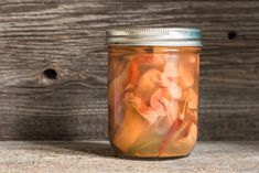 a jar filled with food sitting on top of a wooden table next to a wall