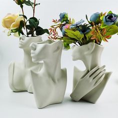 three white vases with flowers in them on a table