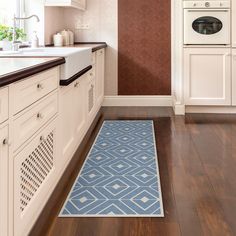 a kitchen with an oven, sink and blue rug on the wooden floor in front of it