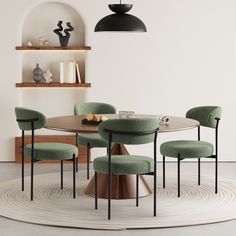 a round table with four green chairs and a black pendant light hanging over the top