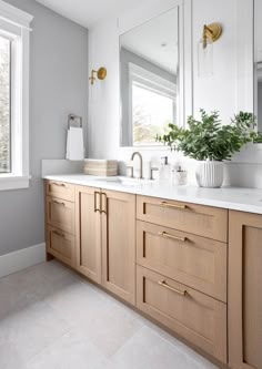 a large bathroom with two sinks, mirrors and plants in vases on the counter