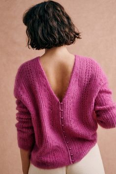 the back of a woman's pink sweater, with her hands in her pockets