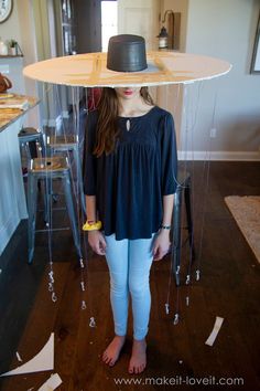 a young woman standing in front of a table with a hat on top of it