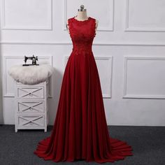 a red evening dress on a mannequin in front of a white wall with a sewing machine