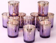 purple glasses with gold speckles are lined up in a pyramid formation on a white surface