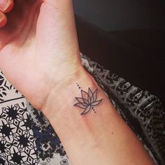 a woman's wrist tattoo with a lotus flower on the left side of her arm