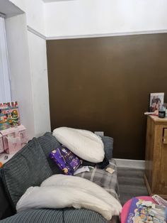 a couch with pillows on it in front of a brown wall and a dresser next to it