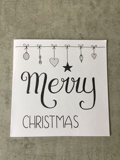 a merry christmas card hanging from a line with ornaments on the top and below it