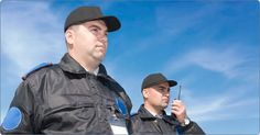 two men in black jackets and hats are standing next to each other, one is holding a cell phone