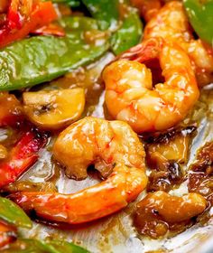 a close up of some food with shrimp and peppers in sauce on a white plate