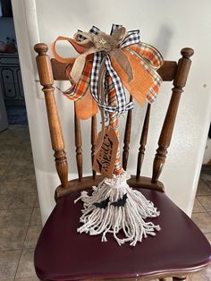 a wooden chair with a bow on the back and tassels attached to it