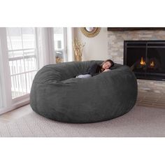 a woman laying in a large bean bag chair next to a fire place and fireplace