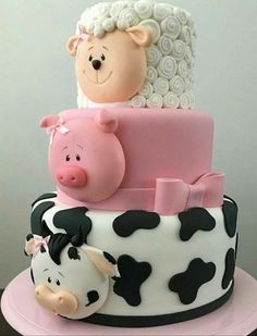 a three tiered cake decorated with pink and black fondant, white frosting, and farm animals