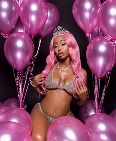 a woman with pink hair is surrounded by balloons