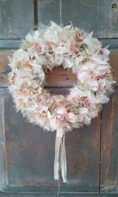 a wreath hanging from the side of a wooden door with flowers on it's front