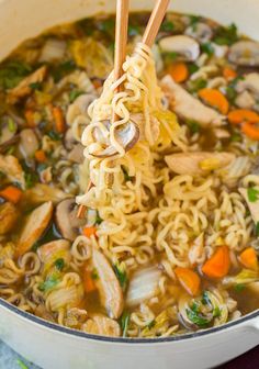 someone holding chopsticks over a bowl of noodles