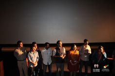 a group of people standing next to each other in front of a projector screen