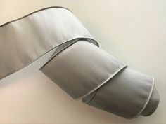 a roll of silver satin ribbon on a white surface with a black stripe at the end