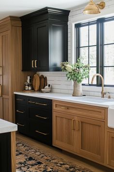 a kitchen with black cabinets, white counter tops and gold pulls on the sink area