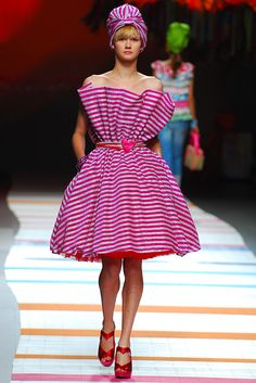 a model walks down the runway in a pink and white striped dress with red heels