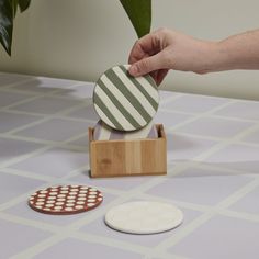 a person is placing a coaster on top of a wooden stand with two matching circles