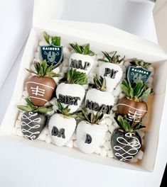 a white box filled with chocolate covered strawberries and topped with green leafy plants