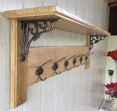 a wooden shelf with metal brackets on it and flowers in vases next to it