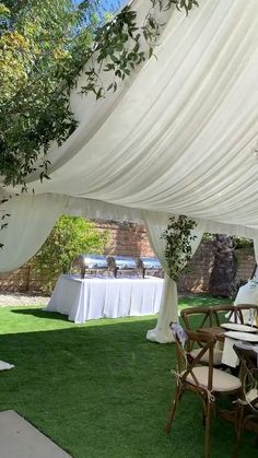 an outdoor dining area with tables and chairs covered in white draping on grass