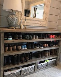 a shelf filled with lots of shoes next to a lamp and mirror on the wall