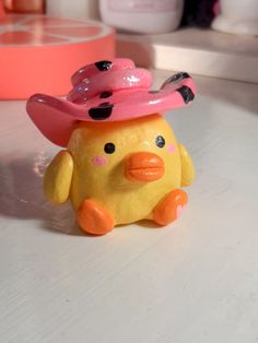 a yellow toy duck with a pink hat on it's head sitting on a table