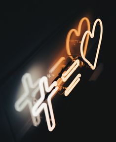 two heart shaped neon signs hanging from the side of a building