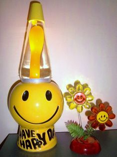 a yellow smiley face lamp sitting on top of a table next to a flower pot