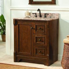 a bathroom vanity with marble top and wooden cabinet, in front of a mirror on the wall