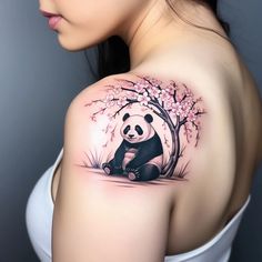 a woman's shoulder with a panda bear tattoo on it and cherry blossom trees