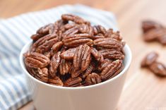 a white bowl filled with pecans on top of a red cloth covered tablecloth